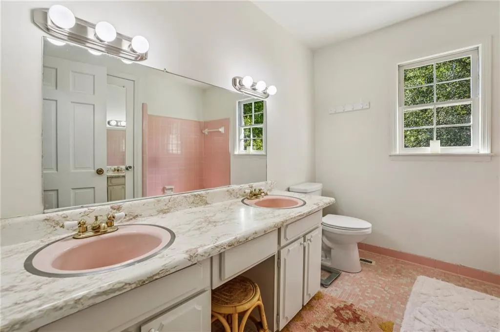 Bathroom with double vanity, a tile shower, and light tile patterned floors