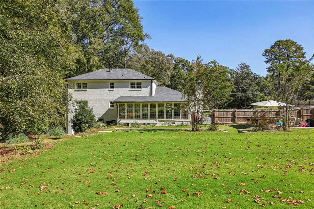Back of house with a sunroom and view of wooded area