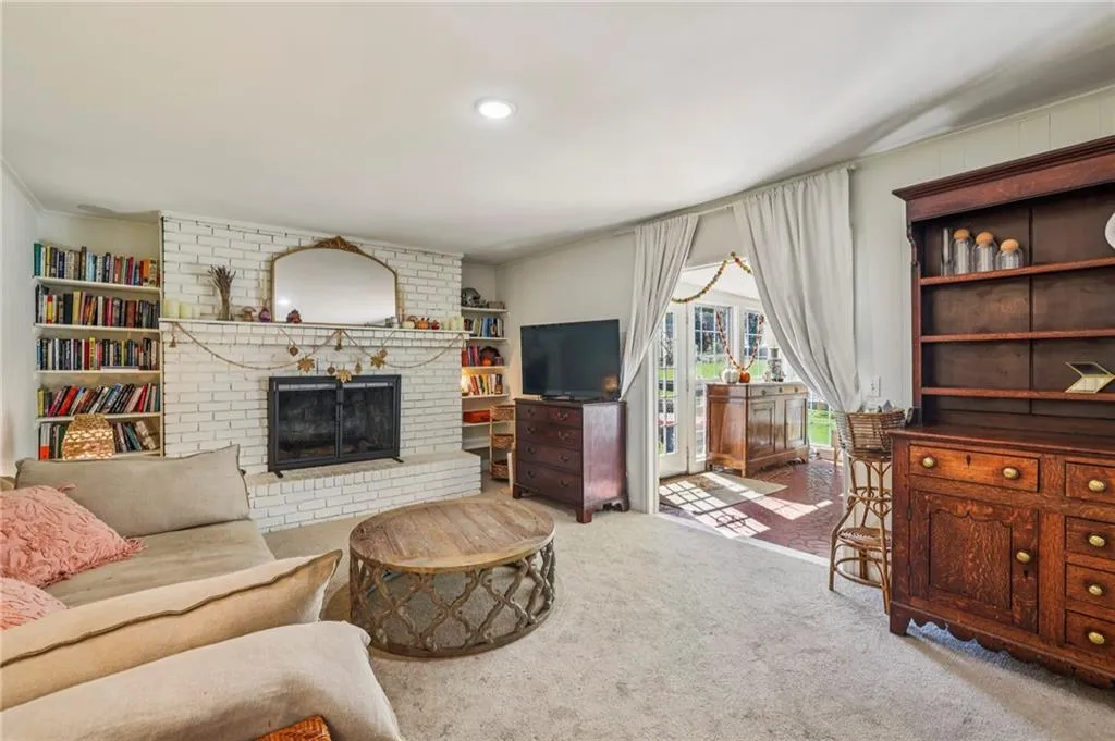 Carpeted living room with a brick fireplace and recessed lighting