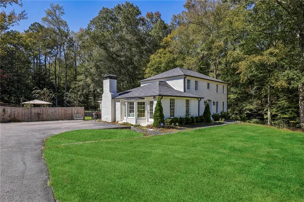 View of front of house with a chimney, brick siding, asphalt driveway, and a shingled roof