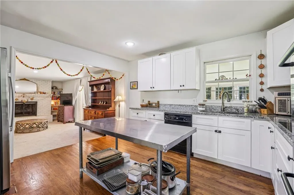 Kitchen featuring white cabinets, dark stone counters, dishwasher, and a fireplace