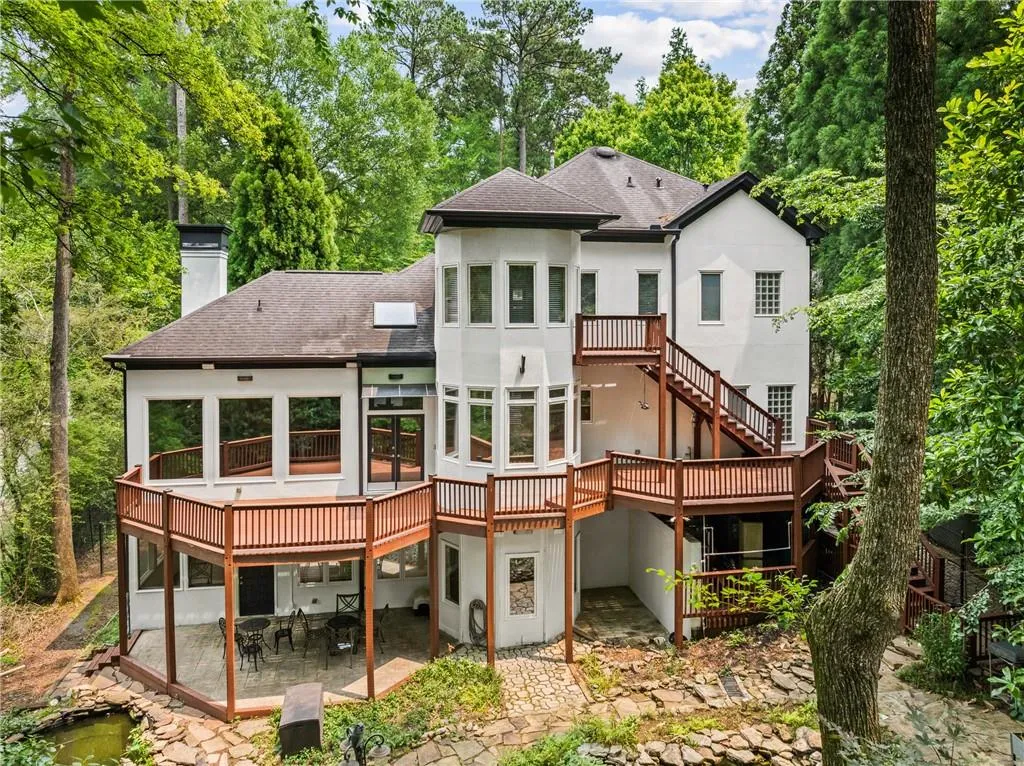 Rear view of property featuring a wooden deck, a patio area, roof with shingles, a chimney, and stucco siding