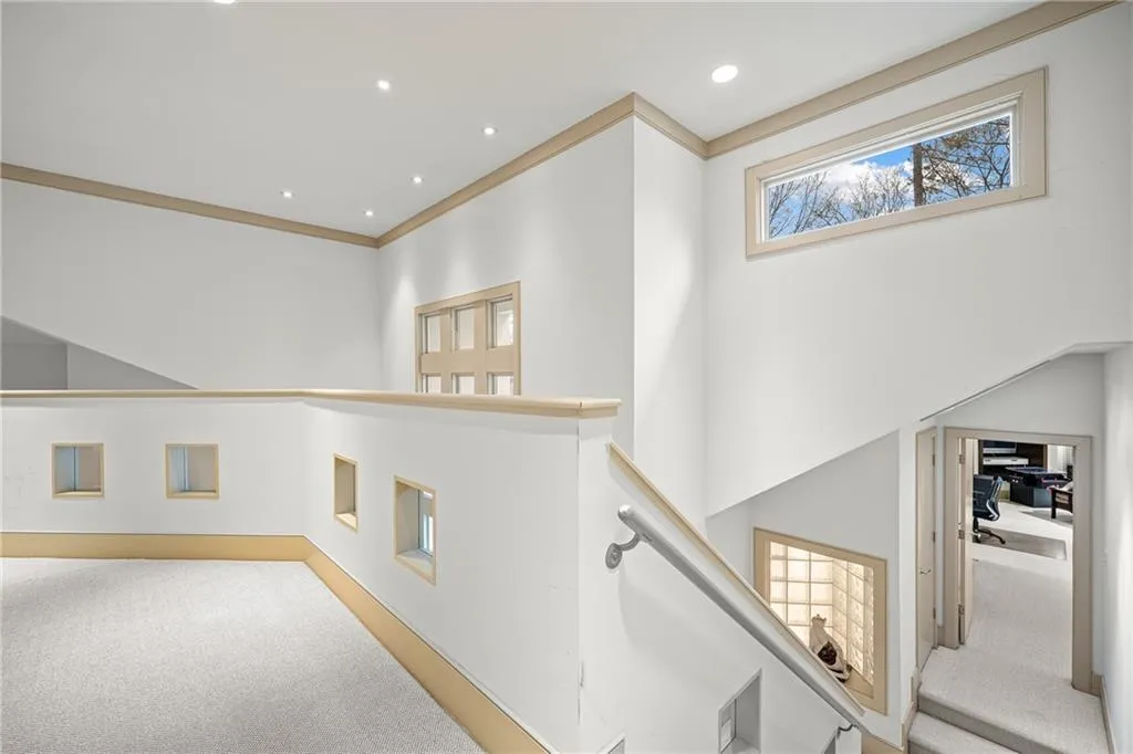 Hallway featuring carpet, a towering ceiling, ornamental molding, recessed lighting, and an upstairs landing