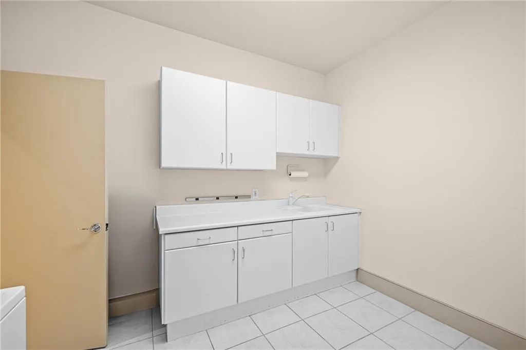 Laundry room featuring light tile patterned floors and a sink