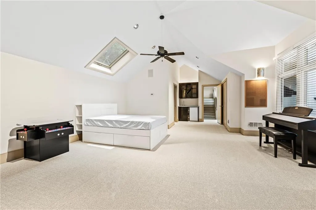 Bedroom featuring carpet floors, vaulted ceiling, a skylight, ceiling fan, and white refrigerator