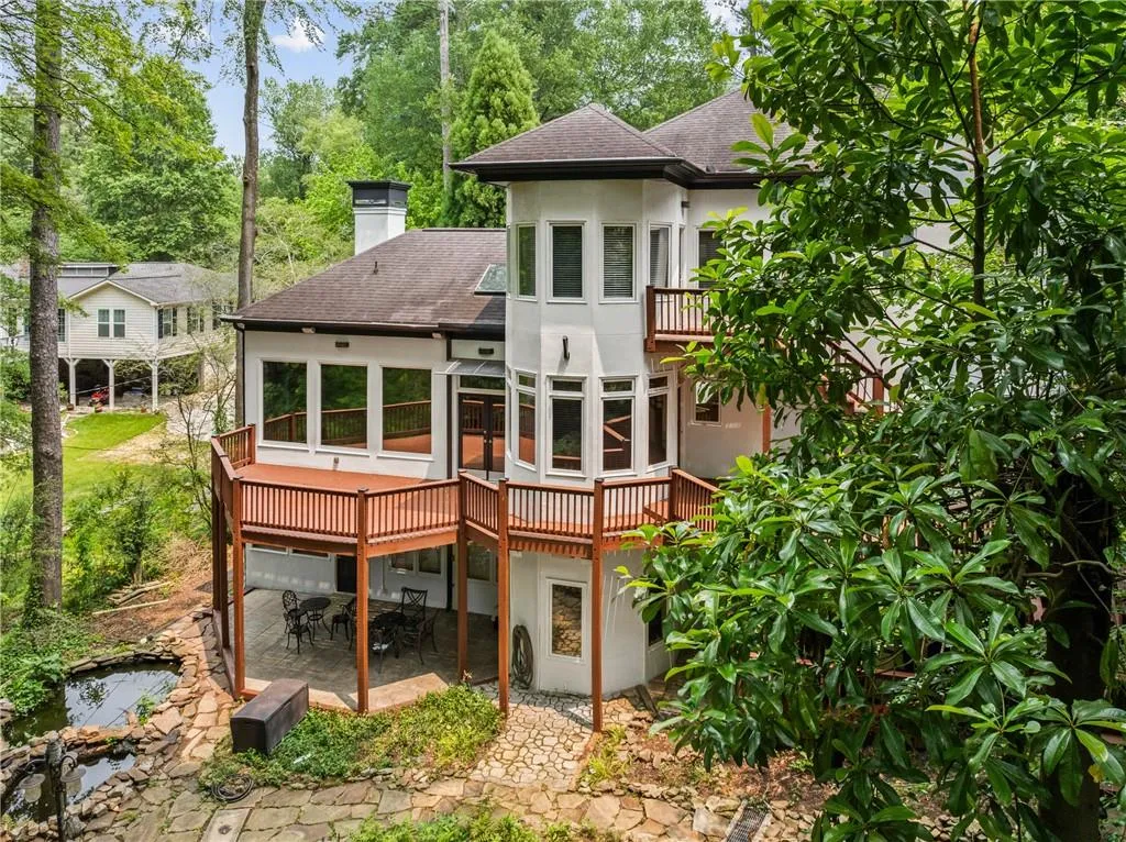 Back of property with a sunroom, stucco siding, a chimney, a patio area, and outdoor dining area