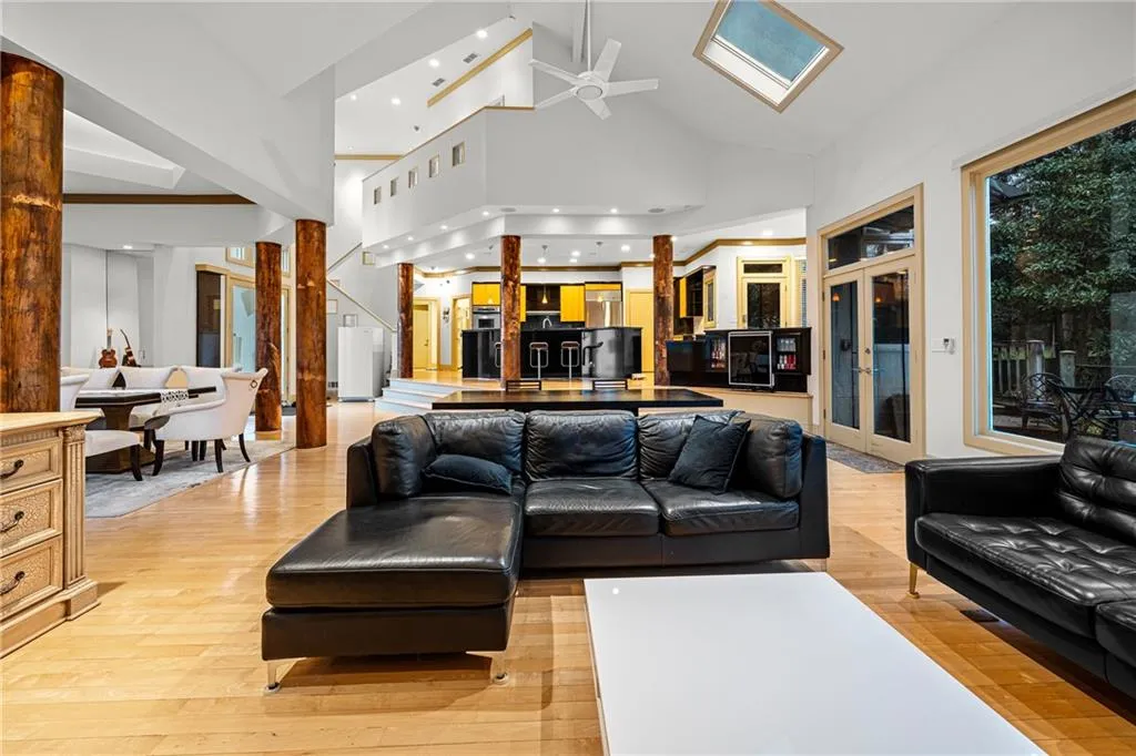 Living area featuring high vaulted ceiling, light wood finished floors, and ceiling fan