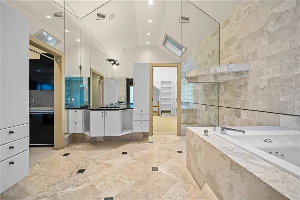 Full bathroom featuring vanity, a whirlpool tub, tile walls, recessed lighting, and high vaulted ceiling