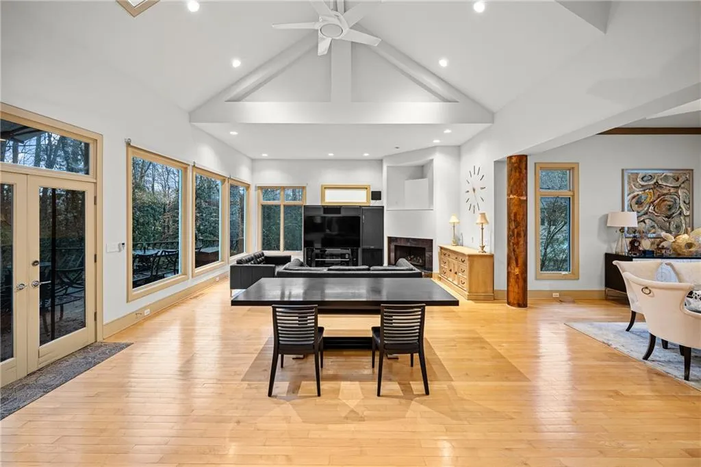 Dining area with high vaulted ceiling, light wood finished floors, plenty of natural light, french doors, and a fireplace