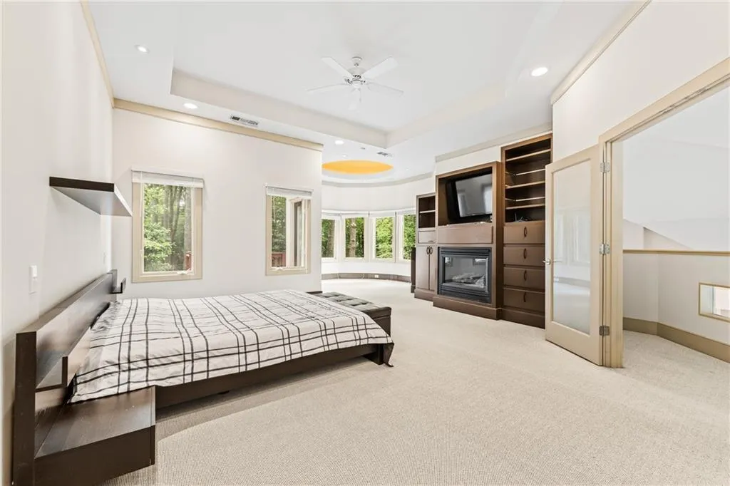 Bedroom with multiple windows, light carpet, a tray ceiling, recessed lighting, and ceiling fan