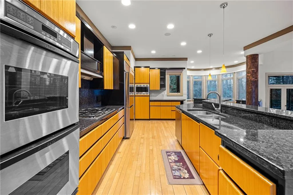 Kitchen with built in appliances, tasteful backsplash, recessed lighting, dark stone countertops, and hanging light fixtures