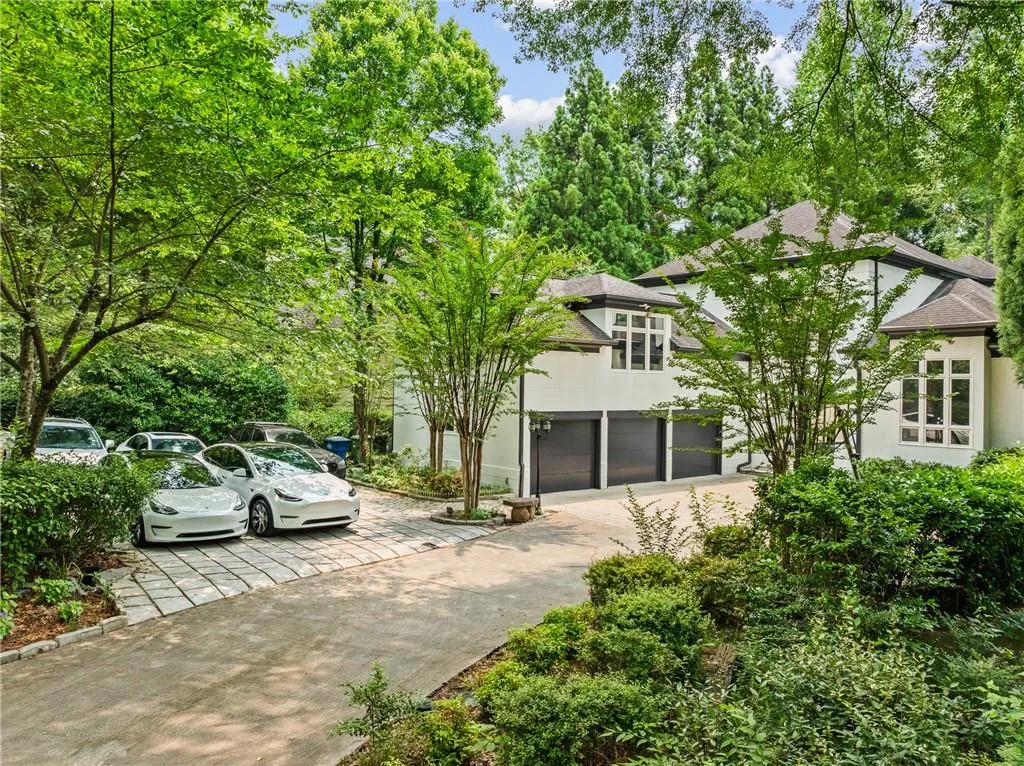 View of front facade featuring concrete driveway, stucco siding, view of wooded area, and a garage