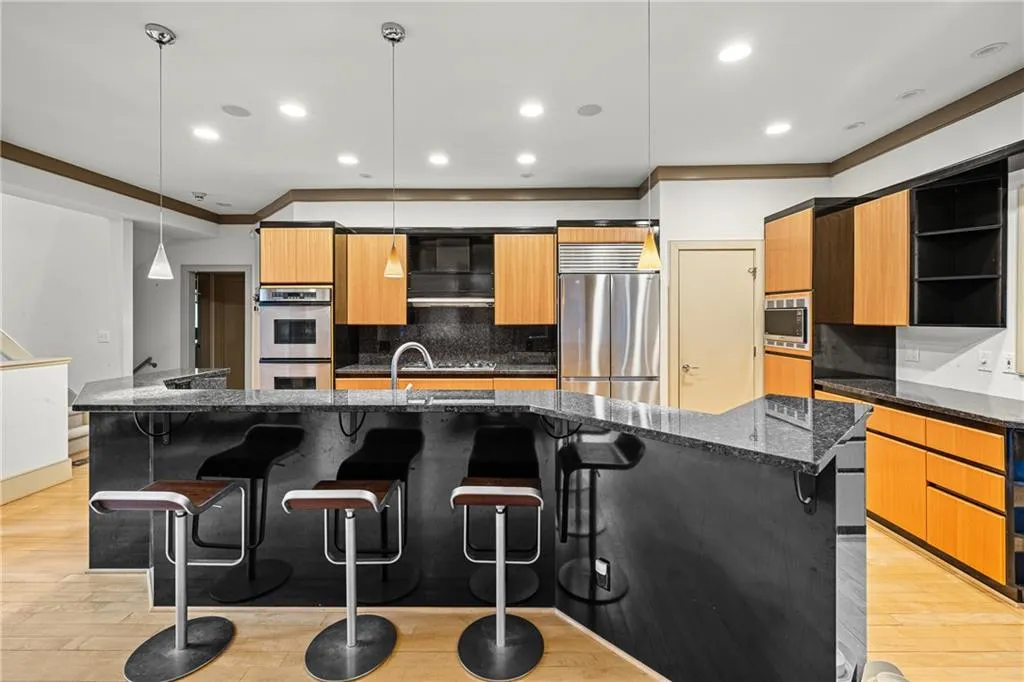 Kitchen with modern cabinets, light wood finished floors, decorative backsplash, pendant lighting, and recessed lighting