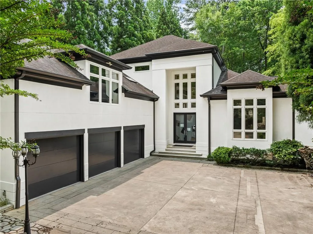 View of front of home featuring stucco siding, roof with shingles, a patio area, and driveway