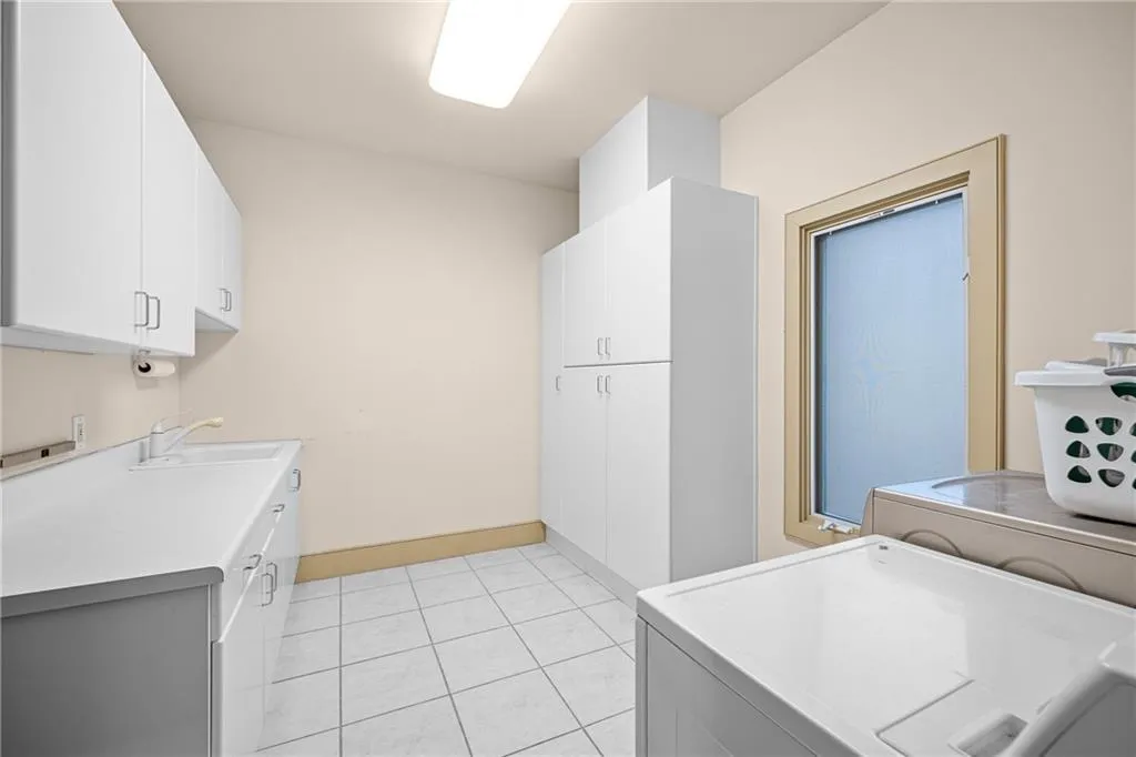 Washroom featuring cabinet space, light tile patterned floors, and independent washer and dryer