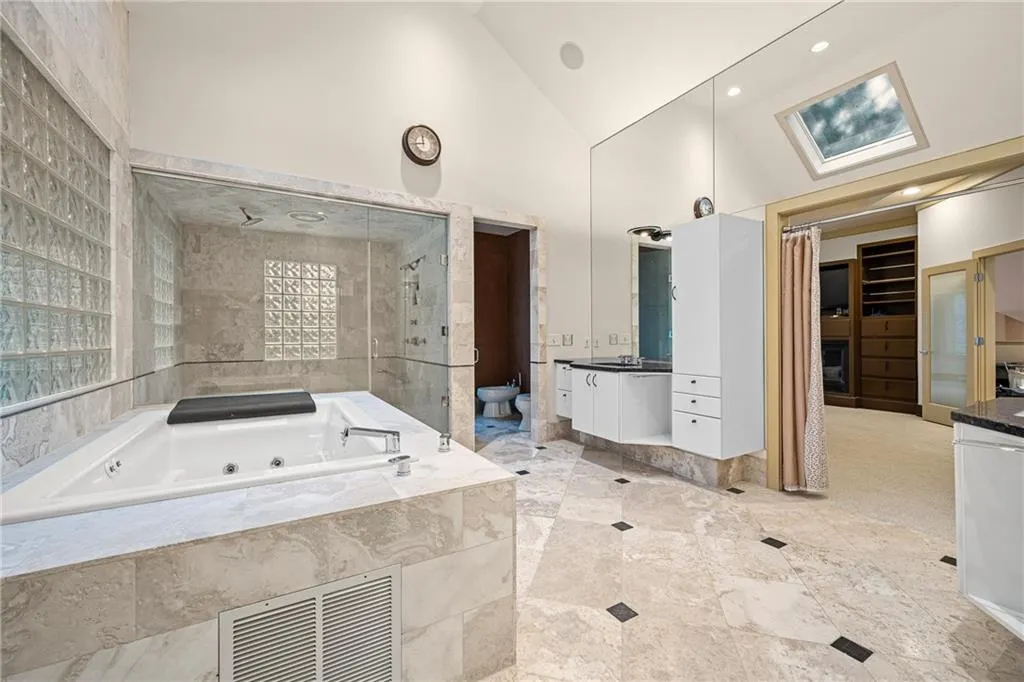 Bathroom with vanity, high vaulted ceiling, a spacious closet, a tub with jets, and a shower stall