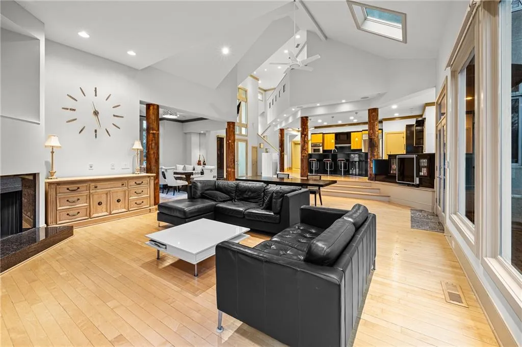 Living room featuring a fireplace with raised hearth, high vaulted ceiling, light wood-style flooring, stairs, and ceiling fan