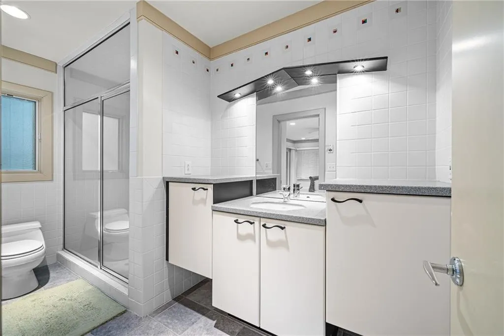 Bathroom with tile walls, a stall shower, vanity, and dark tile patterned floors
