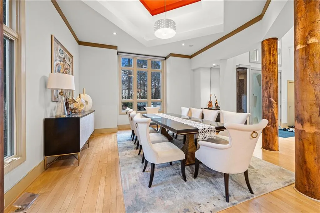 Dining room with a raised ceiling, light wood finished floors, and ornamental molding