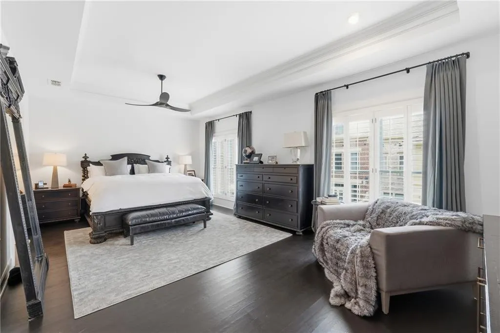 Bedroom with a tray ceiling, ceiling fan, wood finished floors, and crown molding