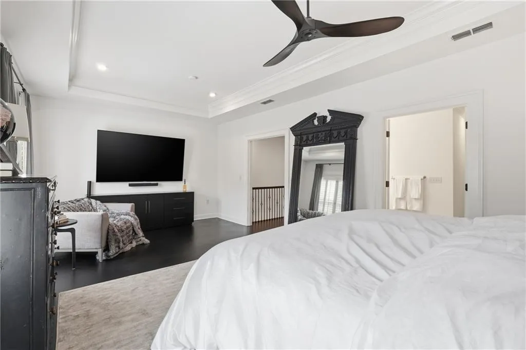 Bedroom featuring a tray ceiling, a ceiling fan, dark wood-style flooring, recessed lighting, and ornamental molding