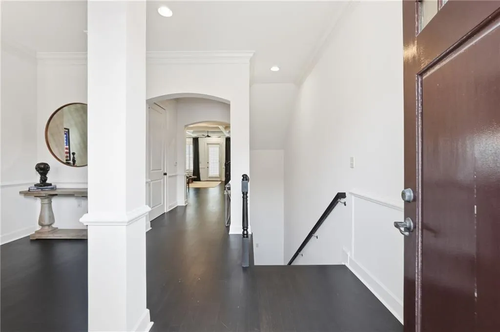 Entryway with arched walkways, crown molding, dark wood-style floors, and recessed lighting