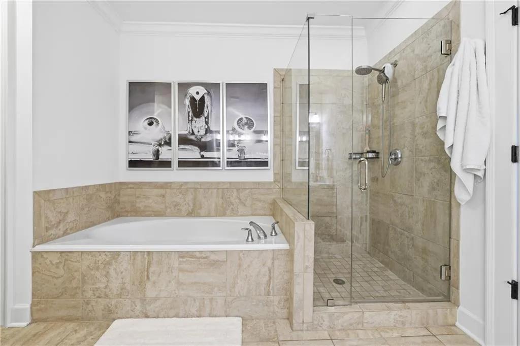 Bathroom with a bath, ornamental molding, and a shower stall