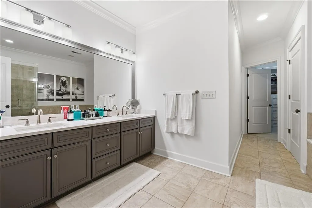 Full bath featuring crown molding, double vanity, a stall shower, recessed lighting, and light tile patterned floors