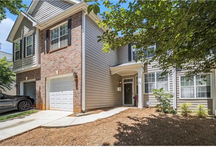 Townhome exterior featuring a combination of brick and siding, a covered entry, a single-car garage with a white panel door, and mature landscaping