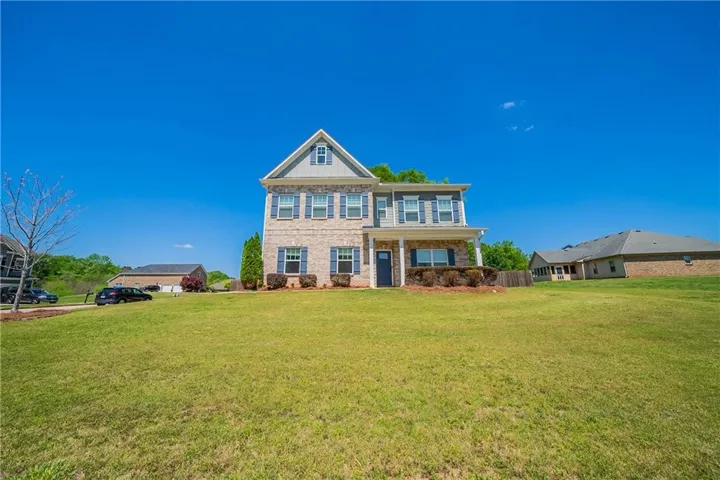 Colonial-style house with a front yard, brick siding, and a porch