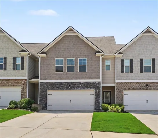 Contemporary townhome community featuring three-unit row configuration with brick and shingle exterior, peaked rooflines, and symmetrical architectural design
