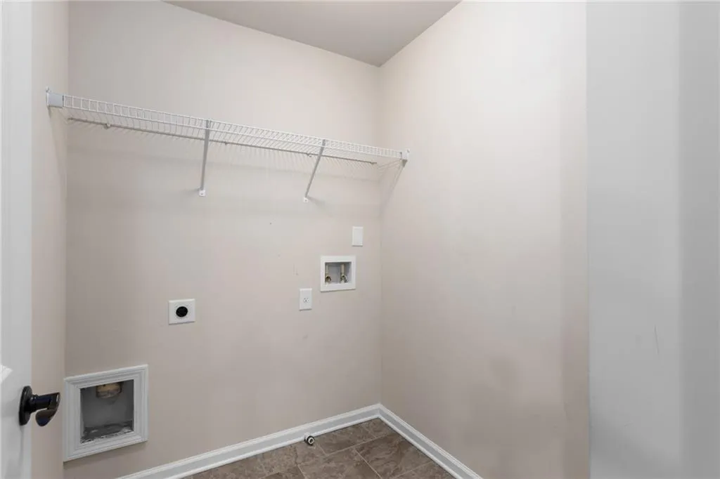 Clothes washing area with dark tile flooring, electric dryer hookup, and hookup for a washing machine