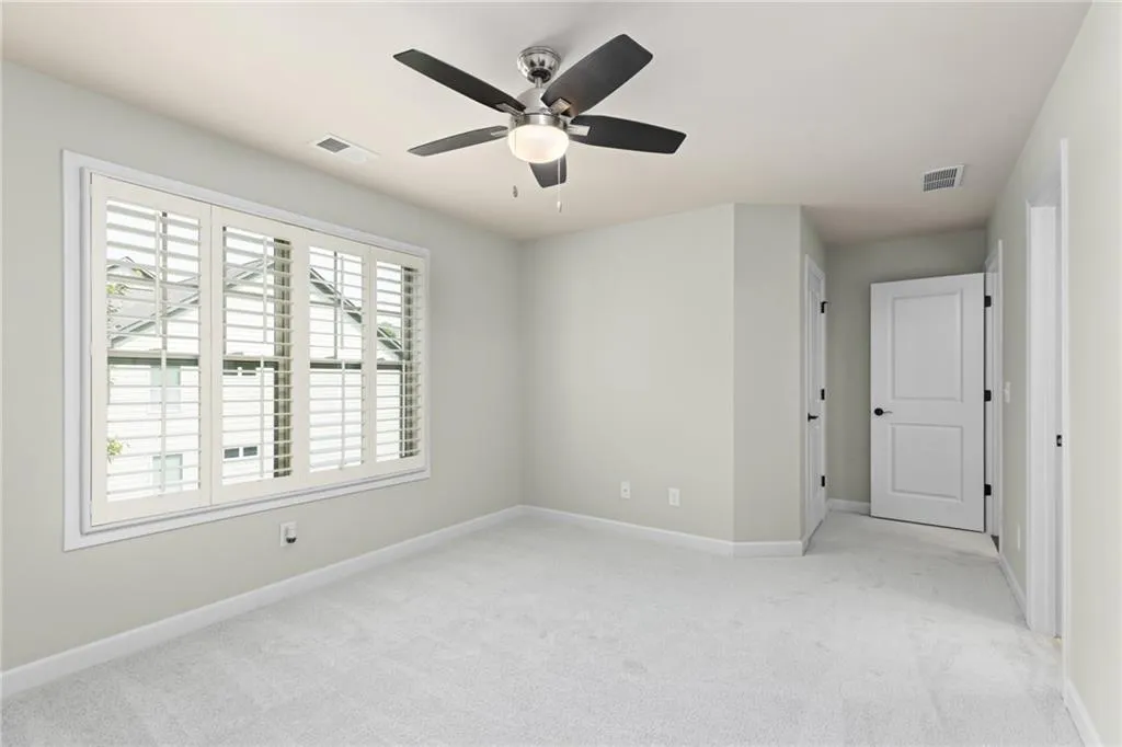 Empty room with ceiling fan and light colored carpet