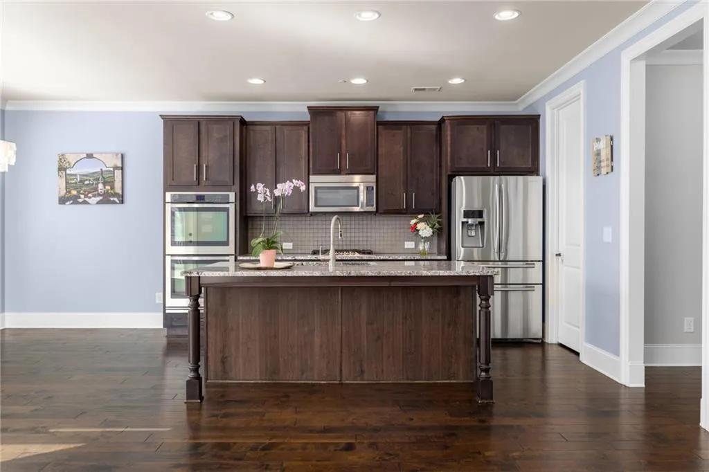 Kitchen with a center island with sink, appliances with stainless steel finishes, and dark hardwood / wood-style flooring