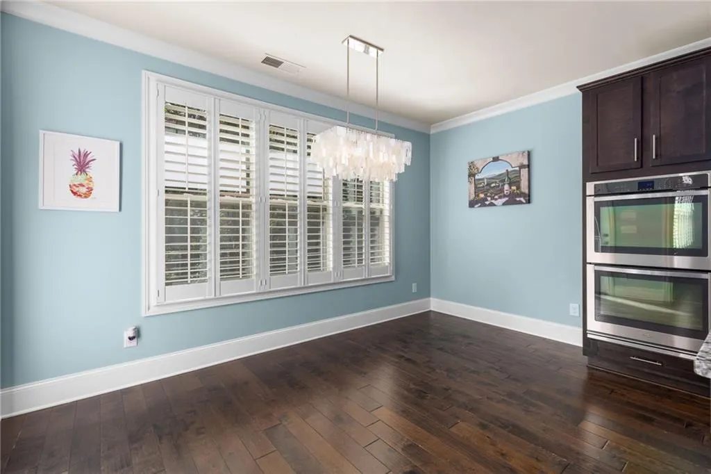 Unfurnished dining area with ornamental molding, dark hardwood / wood-style flooring, and an inviting chandelier