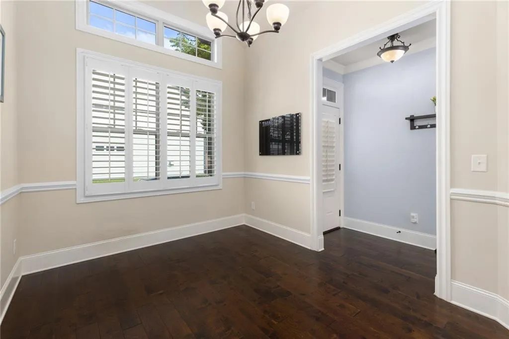 Unfurnished room with a wealth of natural light, a chandelier, and dark wood-type flooring
