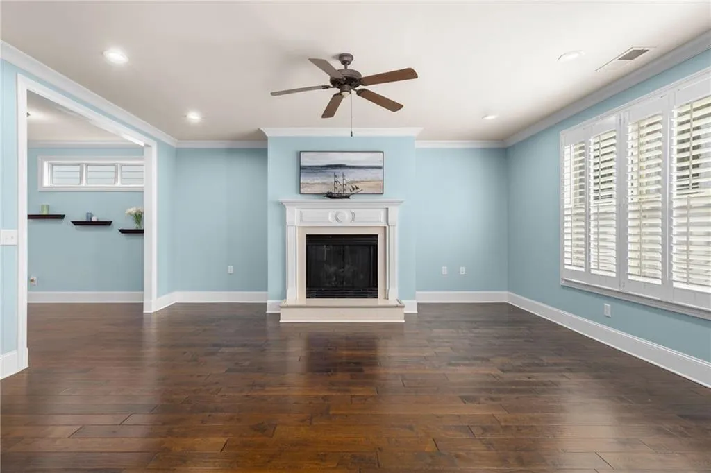 Unfurnished living room with dark hardwood / wood-style flooring, ceiling fan, and crown molding