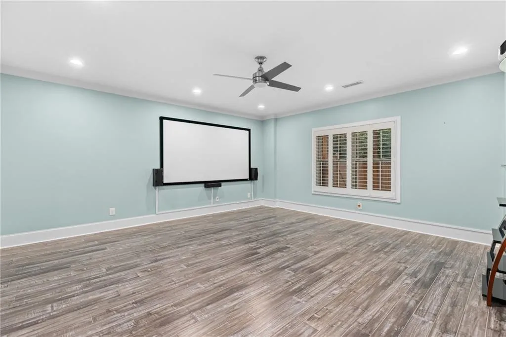 Cinema room featuring ceiling fan and hardwood / wood-style floors