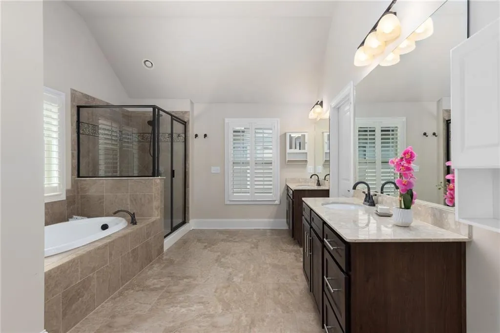 Bathroom featuring shower with separate bathtub, vanity, tile floors, and lofted ceiling