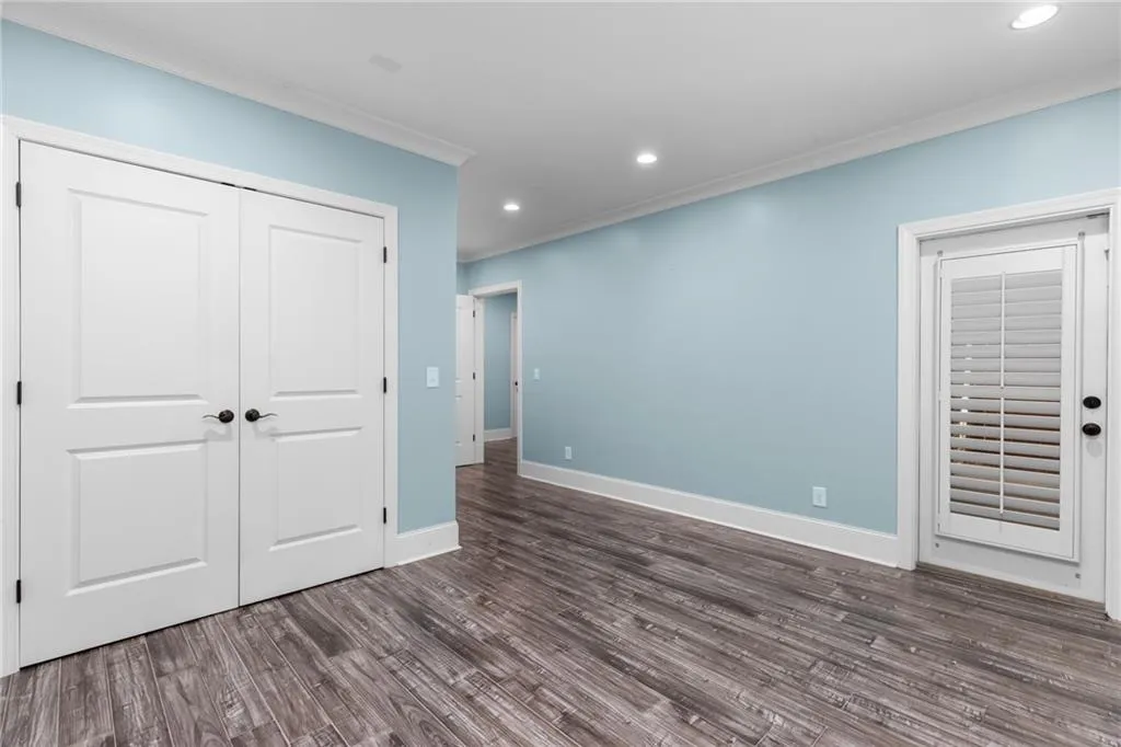 Unfurnished bedroom featuring a closet, ornamental molding, and dark hardwood / wood-style flooring