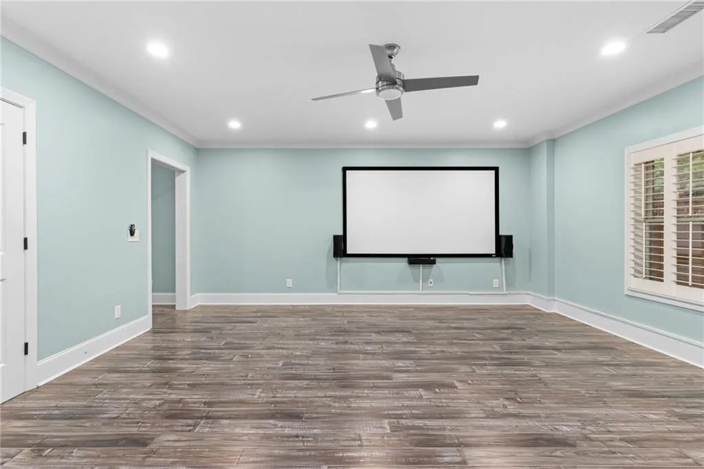 Home theater room featuring wood-type flooring and ceiling fan
