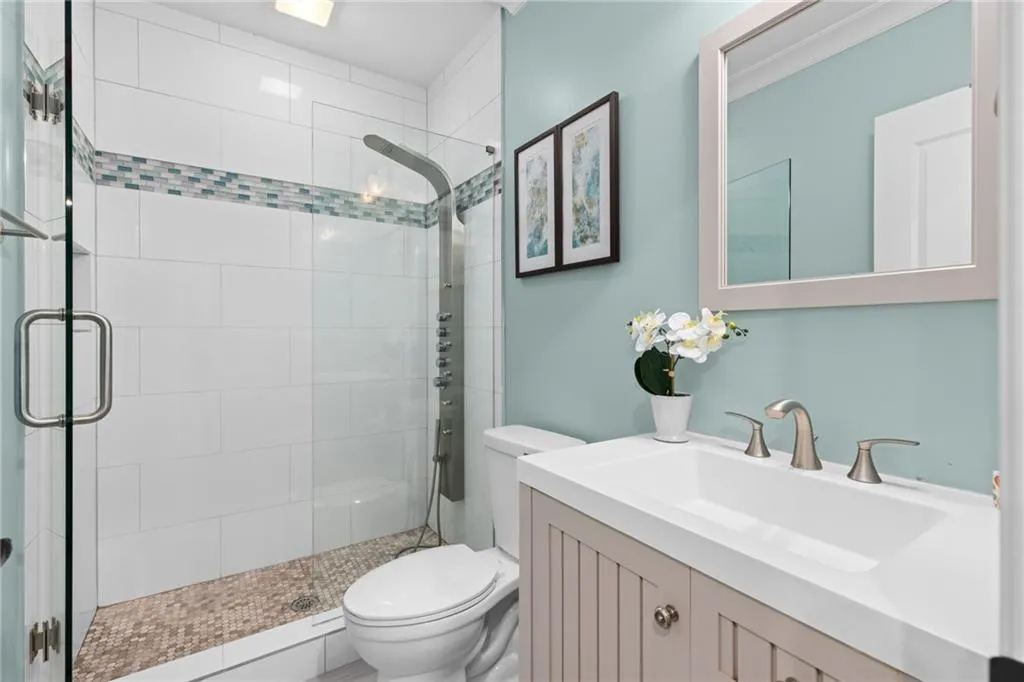 Bathroom featuring a shower with door, toilet, and vanity