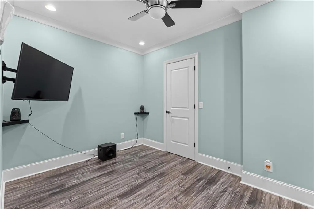 Exercise room with hardwood / wood-style flooring, ornamental molding, and ceiling fan