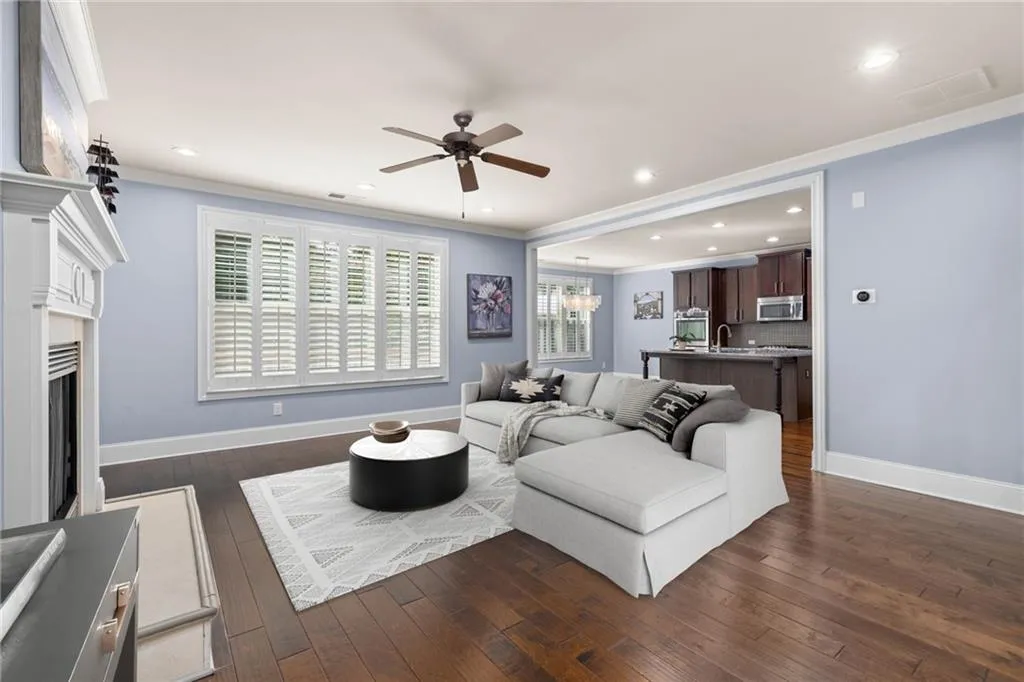 Living room with dark wood-type flooring, sink, ceiling fan, and crown molding
