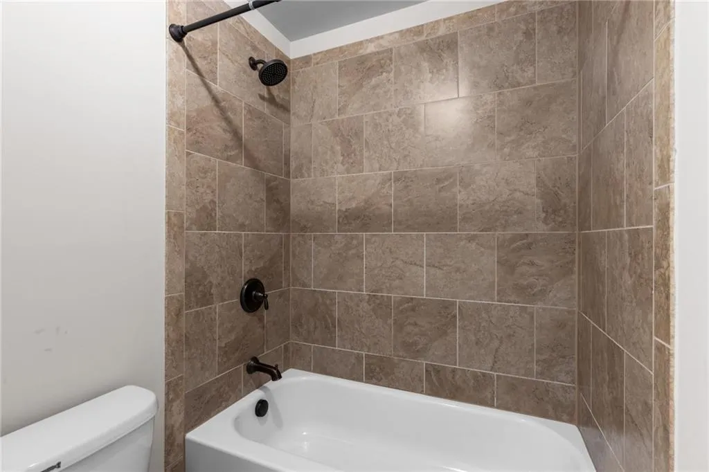 Bathroom with tiled shower / bath and toilet