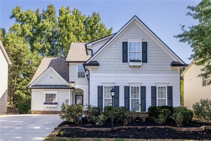 White exterior with dark shutters, gabled rooflines, and a paved driveway