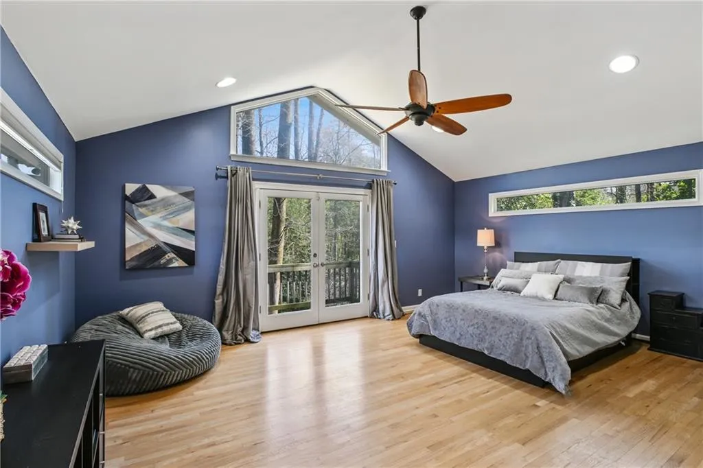 Bedroom featuring access to exterior, vaulted ceiling, light wood-style floors, and french doors