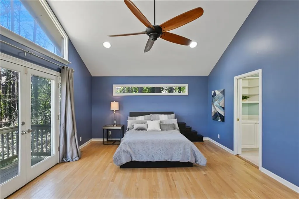 Bedroom featuring access to outside, multiple windows, wood finished floors, and french doors