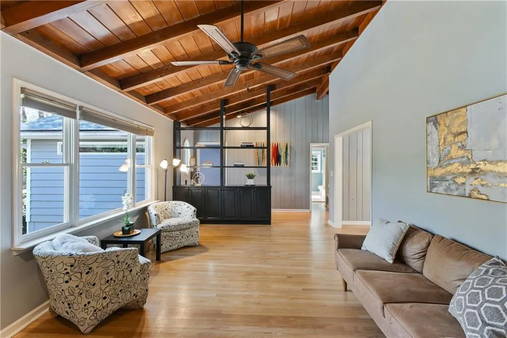 Living area featuring light wood-style flooring, lofted ceiling with beams, a ceiling fan, wooden ceiling, and baseboards