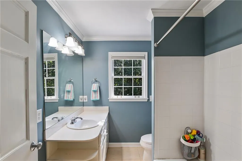 Bathroom featuring a healthy amount of sunlight, toilet, crown molding, and tile patterned floors